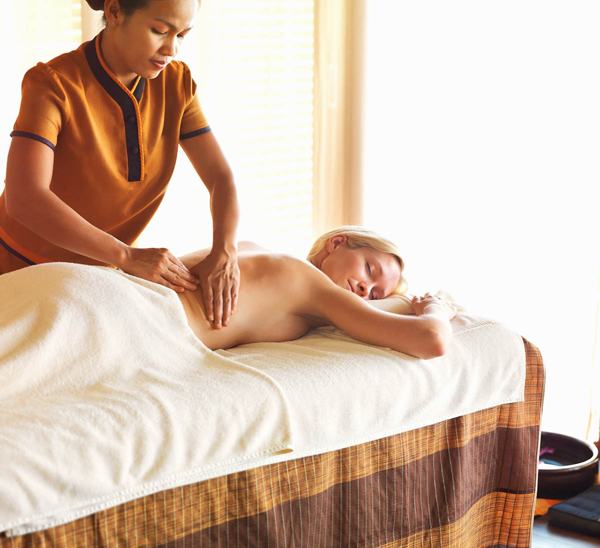 Mixed race masseuse giving relaxing massage to female client at spa